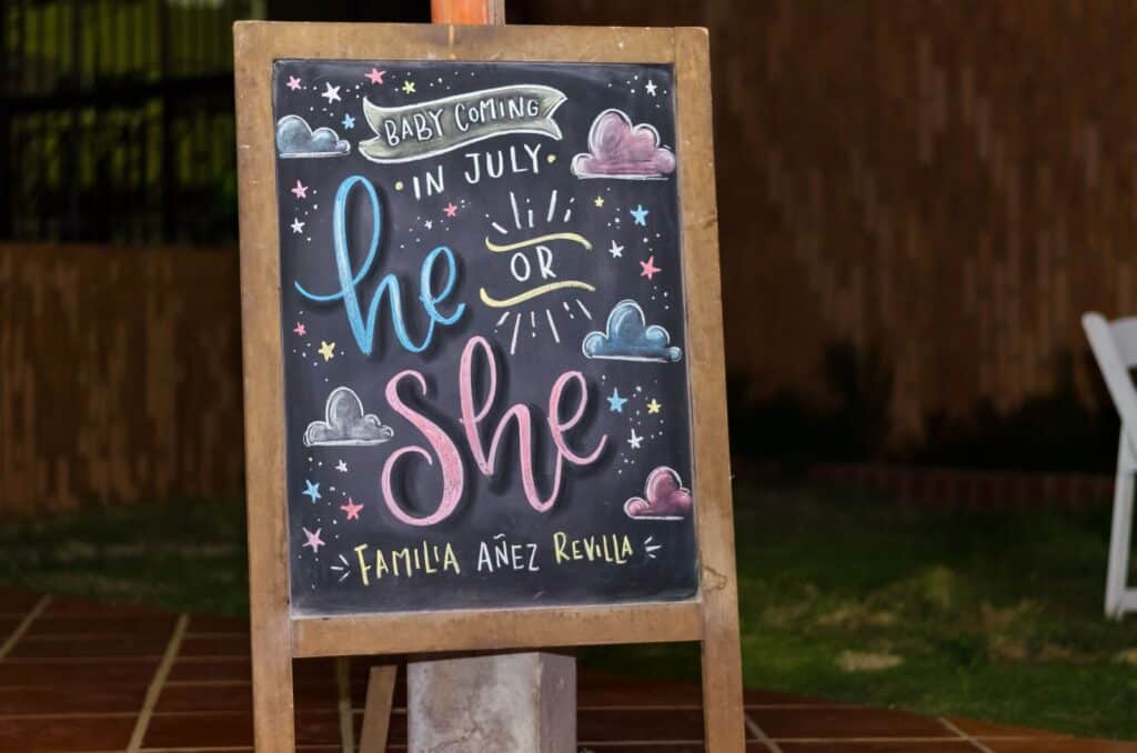 brown framed chalkboard easel with baby coming in July he or she text