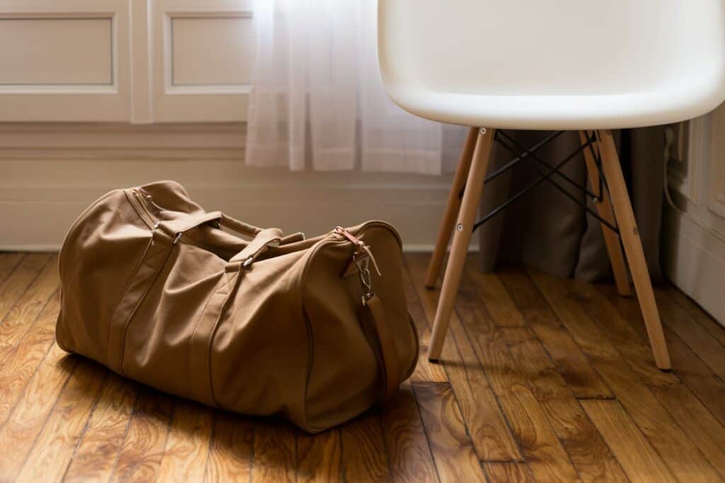 brown duffel bag beside white and brown wooden chair, postpartum essentials