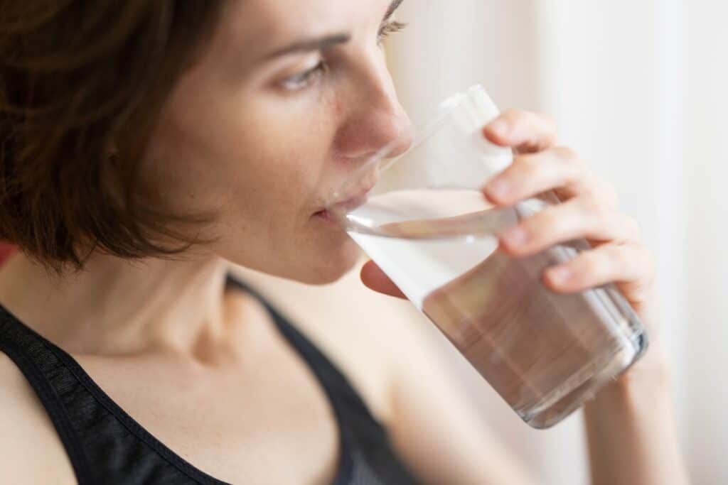 woman in black tank top drinking water, body armor breastfeeding