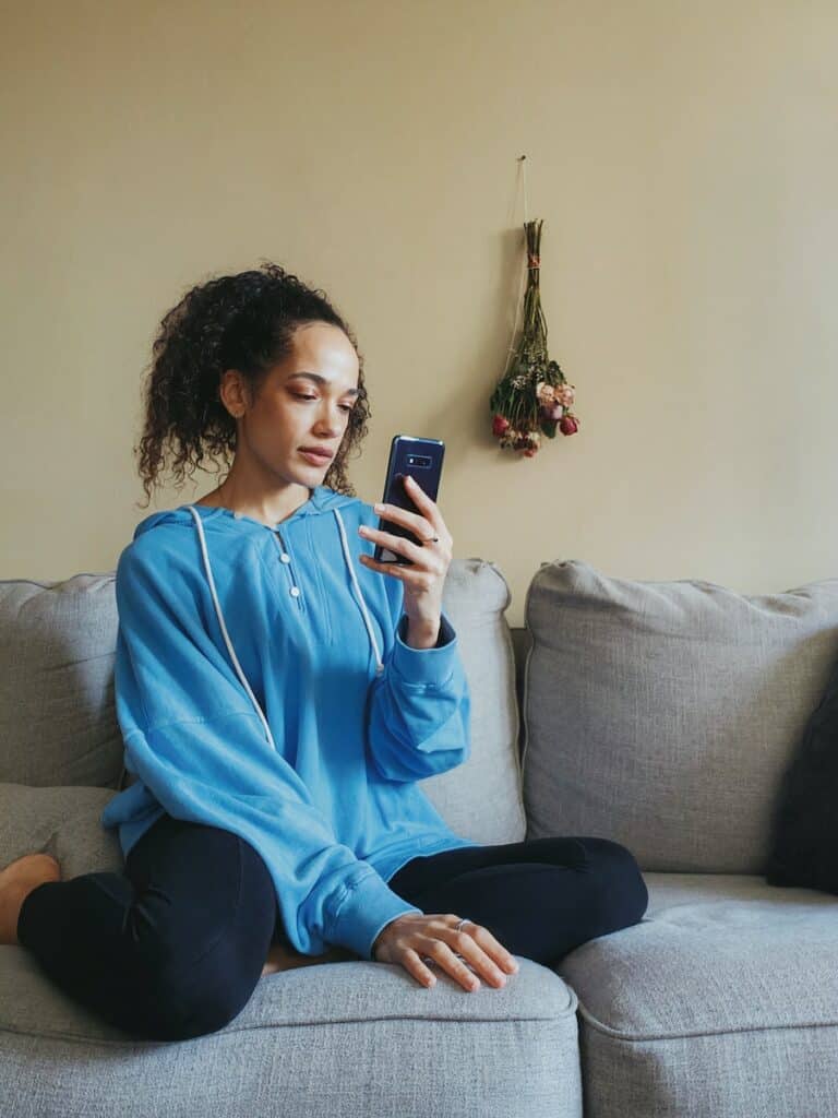 a woman sitting on a couch looking at her cell phone, fertility tracker