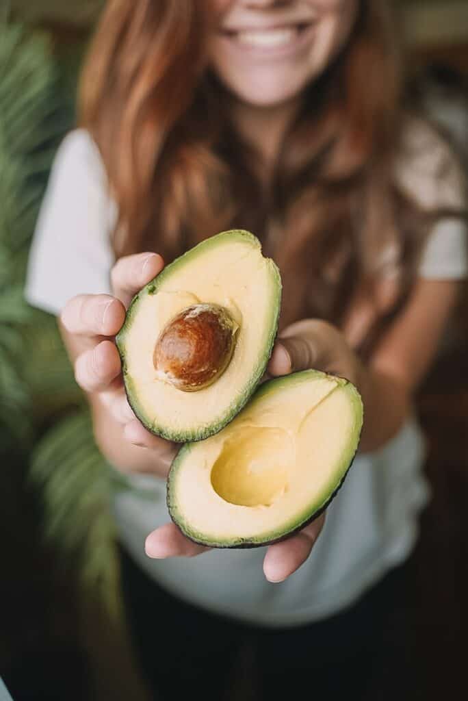 sliced avocado fruit on persons hand is a great fertility food